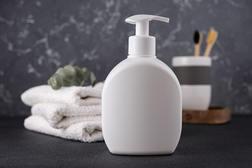 White empty shampoo or lotion bottle for mock-up in modern dark bathroom interior
