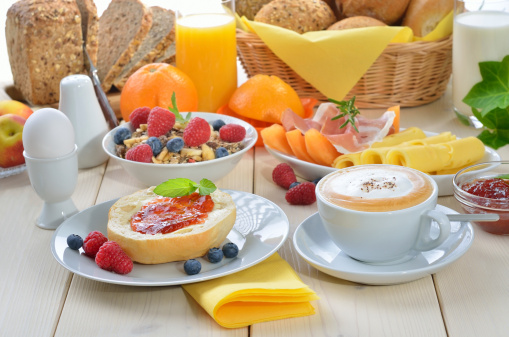 Fresh breakfast with cappuccino, fruit, fresh orange juice, ham, cheese and fresh rolls