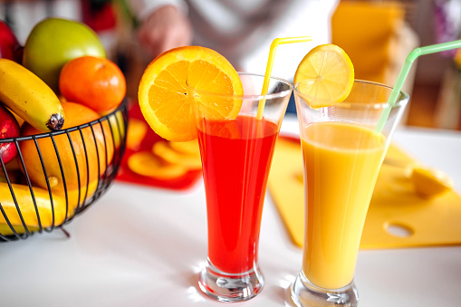 Woman making juice at home using orange and lemon fruit