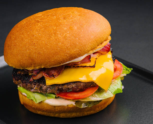istock Close up tall tasty burger with cheese served on tray 1479739020