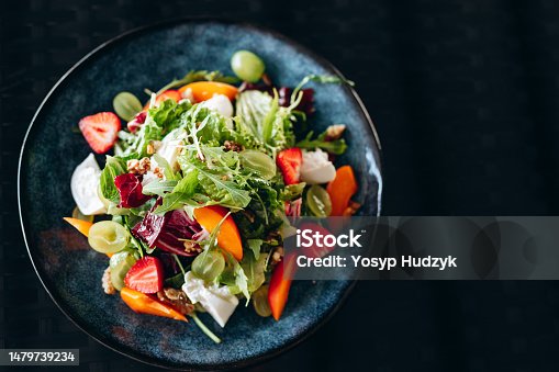 istock Summer salad bowl with grilled sweet peach, soft cheese, walnuts and fresh arugula on black kitchen table, top view. 1479739234