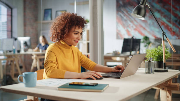 istock Creative Multiethnic Female Working on Laptop Computer in a Company Office. Happy Driven Project Manager Browsing Internet, Writing Tasks, Developing a Marketing Strategy for a Financial Institution. 1479740582
