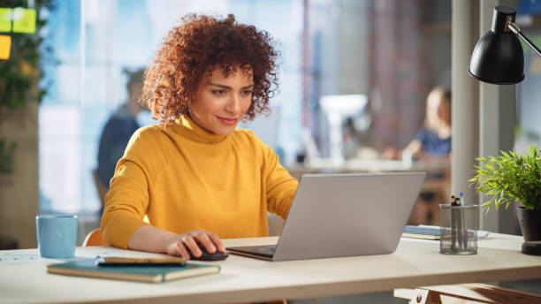 istock Creative Multiethnic Female Working on Laptop Computer in a Company Office. Happy Excited Project Manager Browsing Internet, Writing Tasks, Developing a Marketing Strategy for a Financial Institution. 1479740620