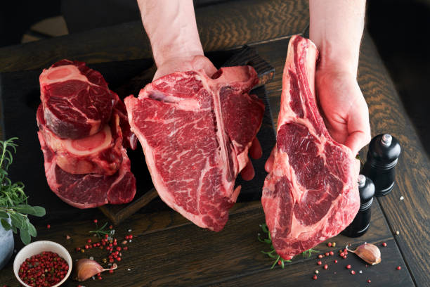 istock Chef cutting steak beef. Mans hands hold raw steak Tomahawk on rustic wooden cutting board on black background. Cooking, recipes and eating concept. Selective focus. 1479741112