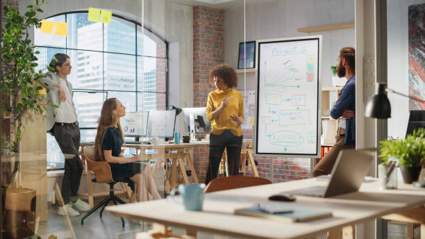 istock Expressive Project Manager Talking on a Team Meeting in Creative Agency Conference Room. Arab Female Showing Business Plan Presentation. Project Plan Presentation on Digital Whiteboard Monitor 1479741182