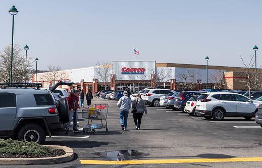 West Homestead, Pennsylvania, USA April 1, 2023 Parked cars and people walking towards the CostCo store on a spring day