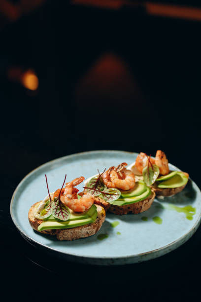 istock Bruschetta with avocado and shrimp, on crispy dried bread, decorated with greens. 1479747507