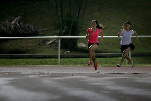 Asian young women are speed running for upcoming track and field 100m race