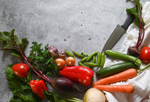 Food cooking background. Fresh rosemary, cilantro, basil, cherry tomatoes, peppers and olive oil, spices herbs and vegetables at black slate table. Food ingredients top view.