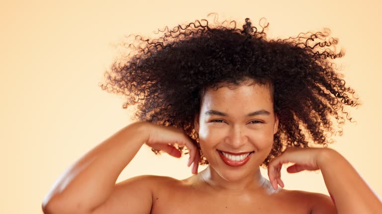 Afro shake, hair care and beauty of woman face in studio isolated on a brown background. Cosmetics, salon and portrait of happy female model with health, wind or texture for curly hairstyle.