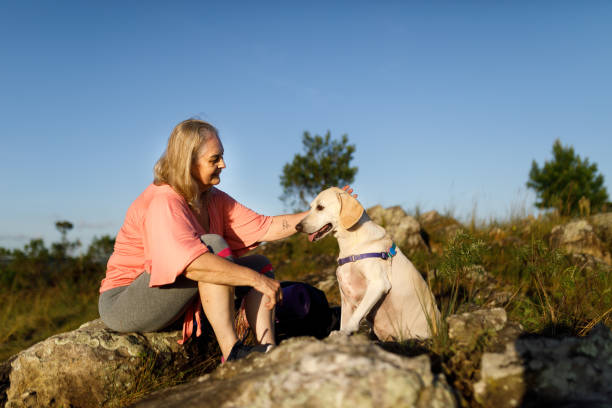 istock Woman sitting on rocks with her dog 1479752847