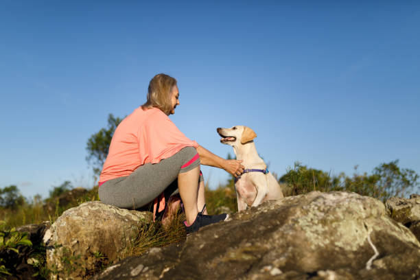 istock Woman sitting on rocks with her dog 1479752851