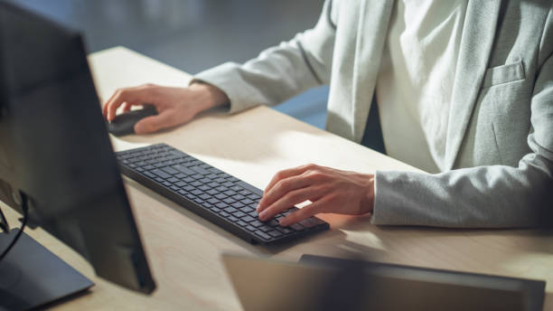 istock Young Male Employee in Gray Casual Jacket Working on Computer in Office During Daytime Close Up on Hands of a Manager Typing Texts on a Keyboard, Writing Text and Using Mouse. 1479756041