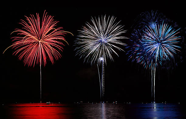 Red, white and blue fireworks set off over lake stock photo