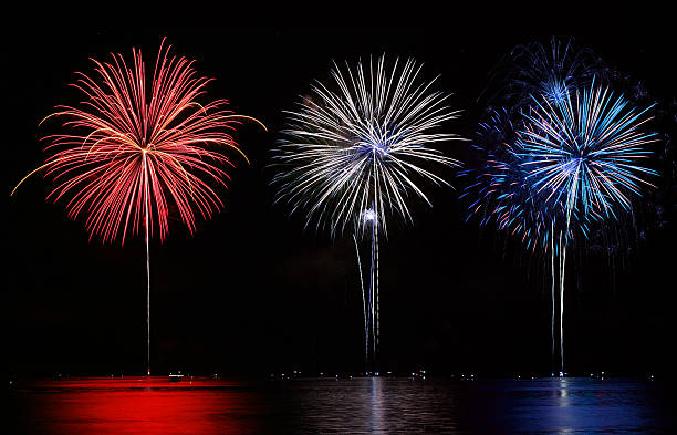 Vermelho, branco e azul conjunto de fogos de artifício sobre o lago - foto de acervo