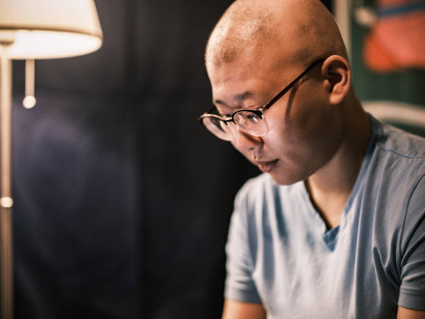 Young Taiwanese LGBTQ woman with Alopecia waking up stock photo