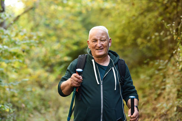 homme âgé rester actif pendant la retraite en faisant de la randonnée dans la nature - pointer stick audio photos et images de collection