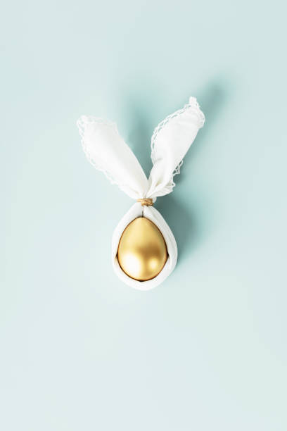 istock Stylish Easter flat lay with golden egg in easter bunny napkin over blue background. Minimalist modern Easter background 1479761262