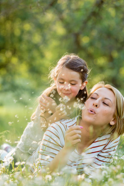 Mother and child having fun blowing dandelion seeds