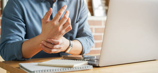 close up employee man massage on his hand and arm for relief pain from hard working for stiff or cramp symptom or carpal tunnel syndrome concept - pijn fotos stockfoto's en -beelden
