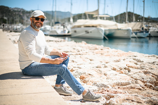 mature adult man walks along the marina with yachts ( with Digital Tablet )