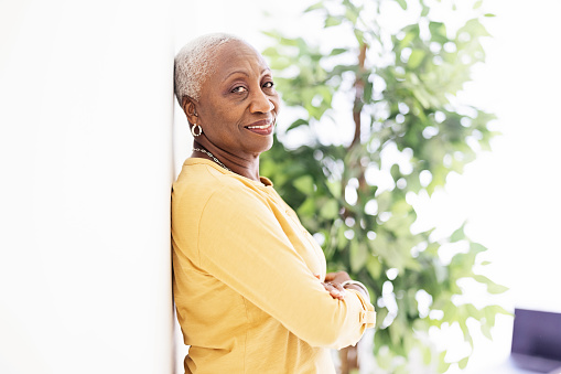 Senior African American woman portrait against a wall, looking at camera with a gentle smile