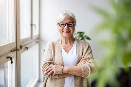 Portrait of a confident senior woman looking at camera and smiling standing outdoors. Happy mature woman with eyeglasses standing outdoors.