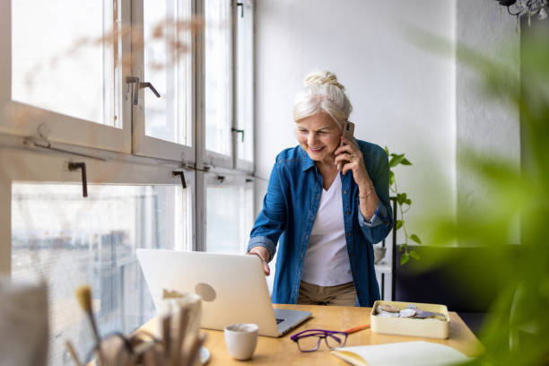 istock Smiling businesswoman talking on mobile phone while using laptop in office 1479775789