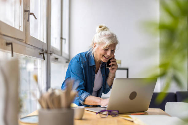istock Smiling businesswoman talking on mobile phone while using laptop in office 1479775790