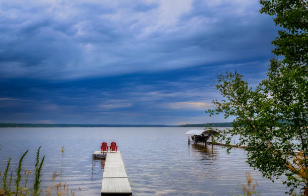 istock Two adirondack chairs on a pier overlooking a lake 1479777327