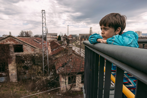 Sad kid looking at abandoned buildings