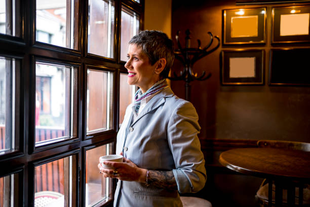 istock Woman with coffee looking through the window 1479779355