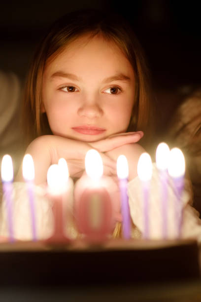 linda niña de diez años pidiendo un deseo antes de soplar velas en su pastel de cumpleaños. niña celebrando su birhday. - celebration 10 11 years birthday cake cake fotografías e imágenes de stock