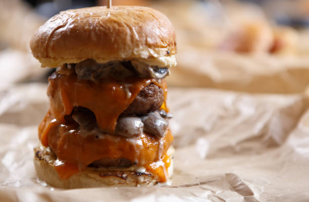 istock Huge double cheese burger for lunch. Unhealthy and fat hamburger with melted cheddar and grilled pork meat 1479780127