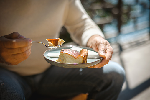 mature adult man eating cheesecake in a street cafe