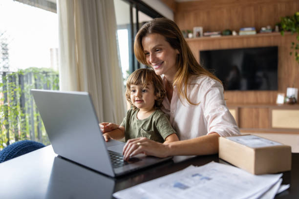 istock Happy mother working on her laptop while taking care of her son 1479782245