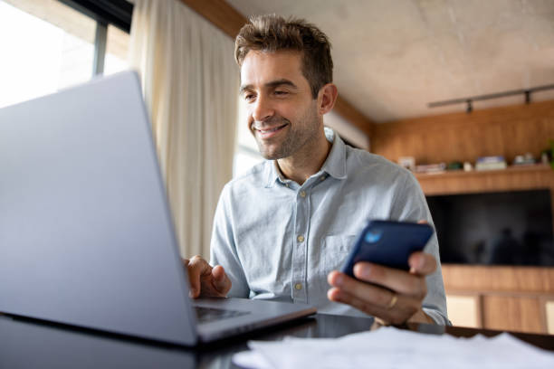 istock Man working at home using his laptop and his cell phone 1479782248