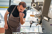 istock Man controlling Coffee Beans in his hands next to Roasting Machine 1479789443