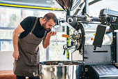 istock Man controlling Coffee Beans in his hands next to Roasting Machine 1479789819