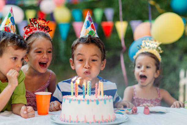 ragazzo che soffia le candeline di compleanno su una festa di birtday - birthday present family facial expression birthday foto e immagini stock