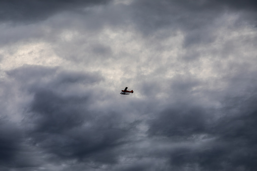 Solo Pilot Seaplane Flying High in the Stormy Overcast Moody Sky