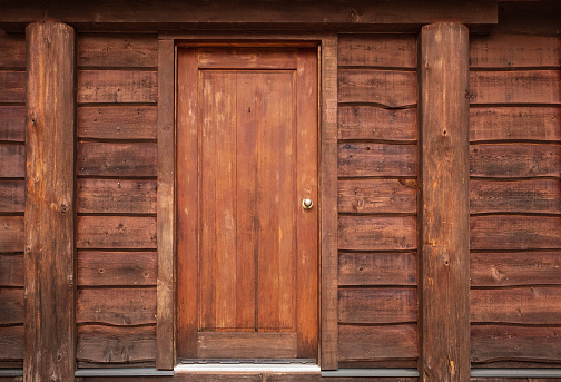 Wooden Front Door in to rustic cabin. Rustic log cabin with front door in the forest BC. Wooden wall with old door. Nobody, selective focus