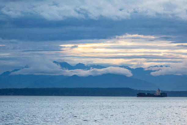 istock Cargo Ship Shipping in Beautiful Scenic Ocean Harbor at Dusk Clouds in the Sky Mountain Range in Background 1479794237