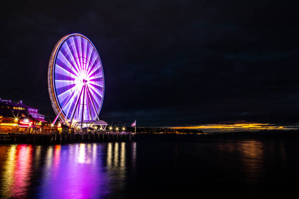 Seattle Washington, The Seattle Great Wheel Lit Up at Night, Reflecting on Pacific Ocean, Harbor Pier 69, Long Exposure, Lights Glowing, Overcast Sky, Gold Clouds in Distance
