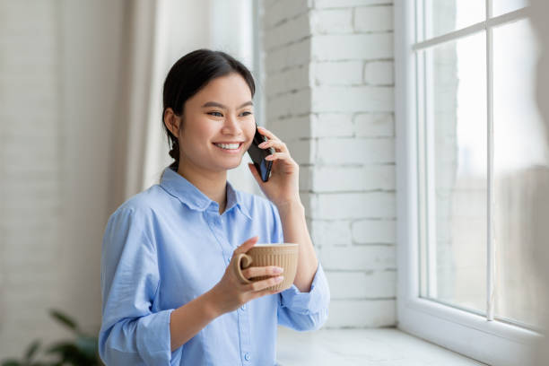 istock Cute japanese lady drinking coffee and talking on phone 1479794667