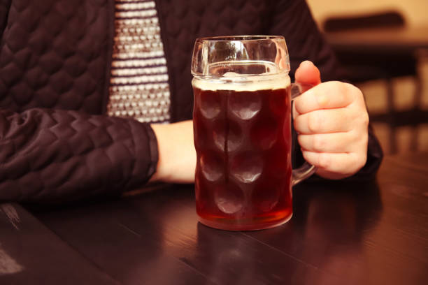 Dark beer. Defocus mug of dark beer. Closeup of two hands clinking beer stein glasses. People, woman or man drinking beer in pub. Beer background. Out of focus Dark beer. Defocus mug of dark beer. Closeup of two hands clinking beer stein glasses. People, woman or man drinking beer in pub. Beer background. Out of focus. large german beer steins stock pictures, royalty-free photos & images
