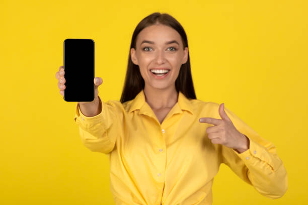 istock Happy Woman Showing Smartphone Empty Screen Over Yellow Background 1479797329