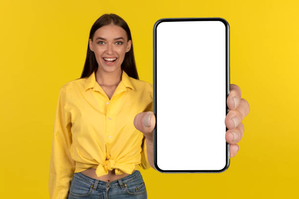 istock Cheerful Female Showing Large Cellphone Screen Over Yellow Background 1479797346