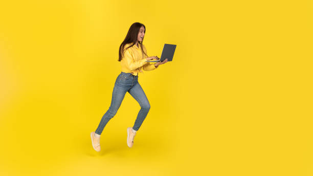istock Excited Freelancer Woman Using Laptop Running In Air, Yellow Background 1479797364