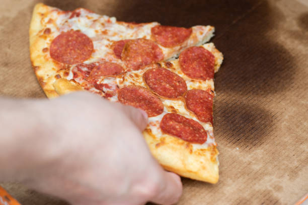 istock Hand taking a piece of pizza 1479797497